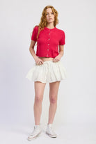 Fuchsia cropped cardigan styled with white mini skirt, full body view
