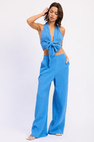 Model wearing blue wide leg cotton gauze pants with elastic waist, styled with matching halter tie top