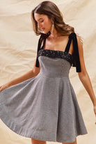 Black and white houndstooth fit and flare dress with sequin neckline trim and tie shoulder straps