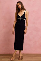 Angled front view of black contrast trim knit midi dress featuring a fitted silhouette and tie neckline | AVAH Collections
