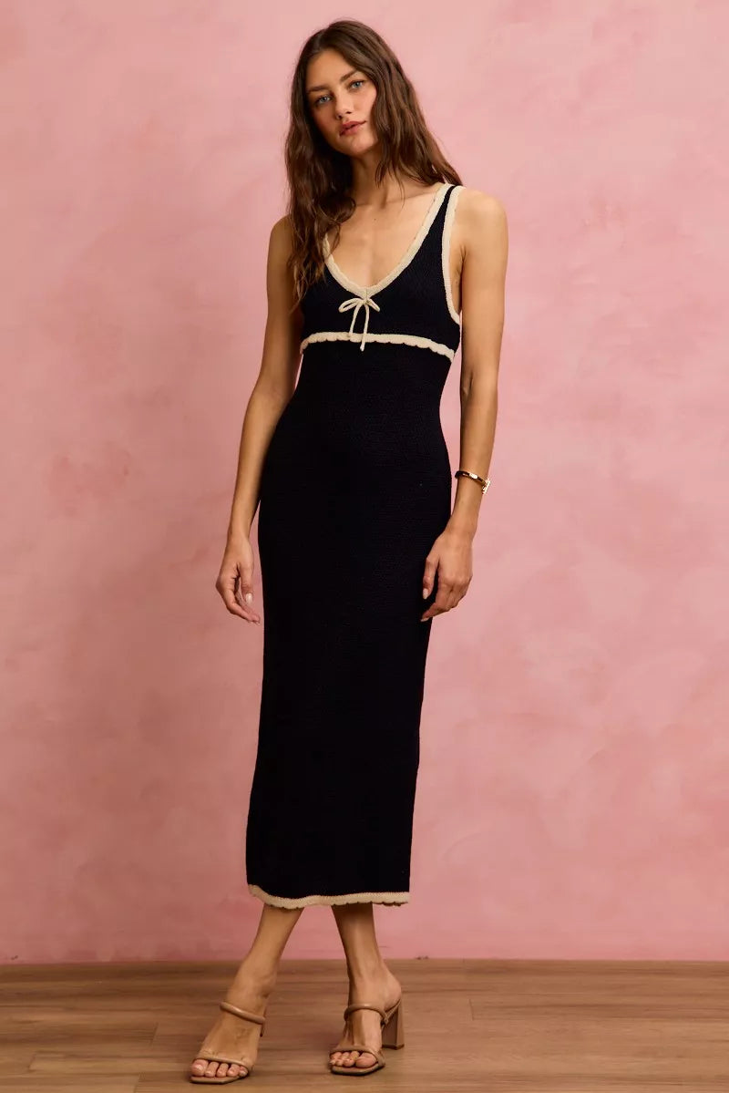 Angled front view of black contrast trim knit midi dress featuring a fitted silhouette and tie neckline | AVAH Collections
