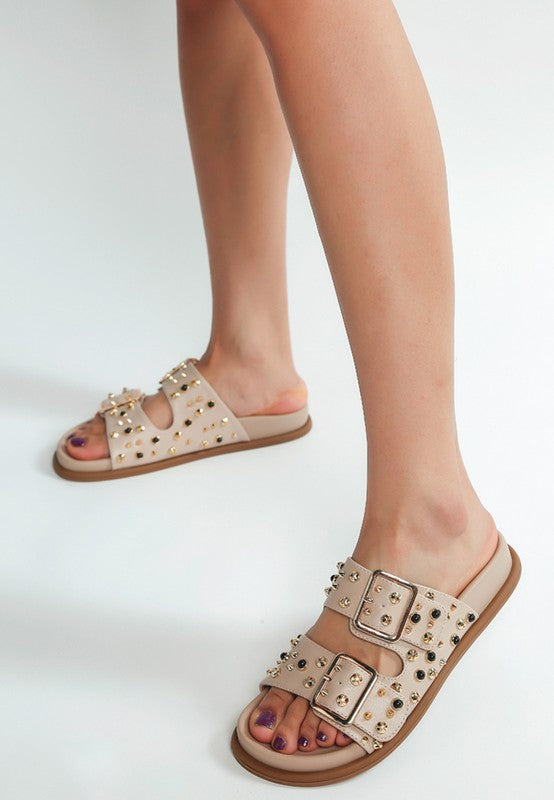 Beige studded slide sandals styled on foot with double buckle straps and gold accents-AVAH