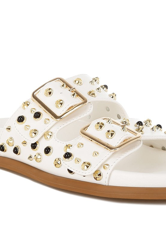 Close-up of white double buckle sandal with metallic studs on faux leather