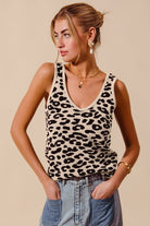 model wearing a beige and black leopard print sweater tank featuring a V neckline and sleeveless knit silhouette styled with light wash denim.