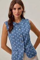 Woman styling tailored polka dot denim vest with white pants
