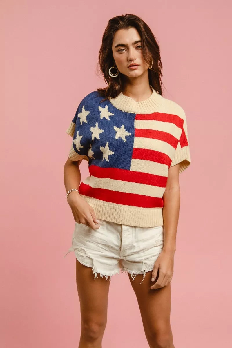 AVAH - model wearing a cream knit sweater top featuring an American flag design with stars and stripes, short sleeves, and a relaxed silhouette.