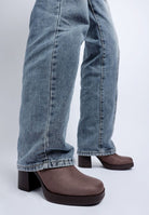 Taupe shoes worn with blue jeans on a white background