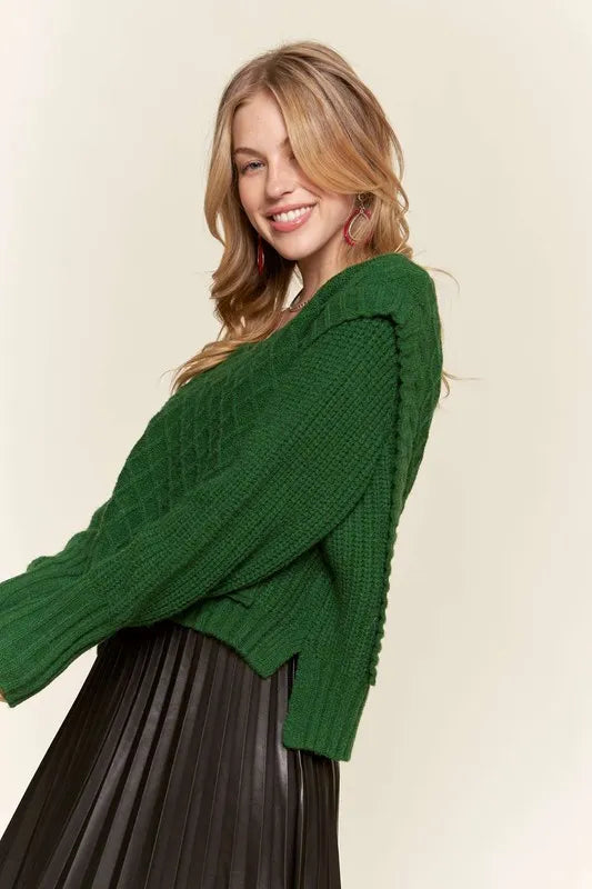 Side view of Emerald Isle green cable knit sweater showing relaxed sleeves, ribbed cuffs and cropped silhouette.
