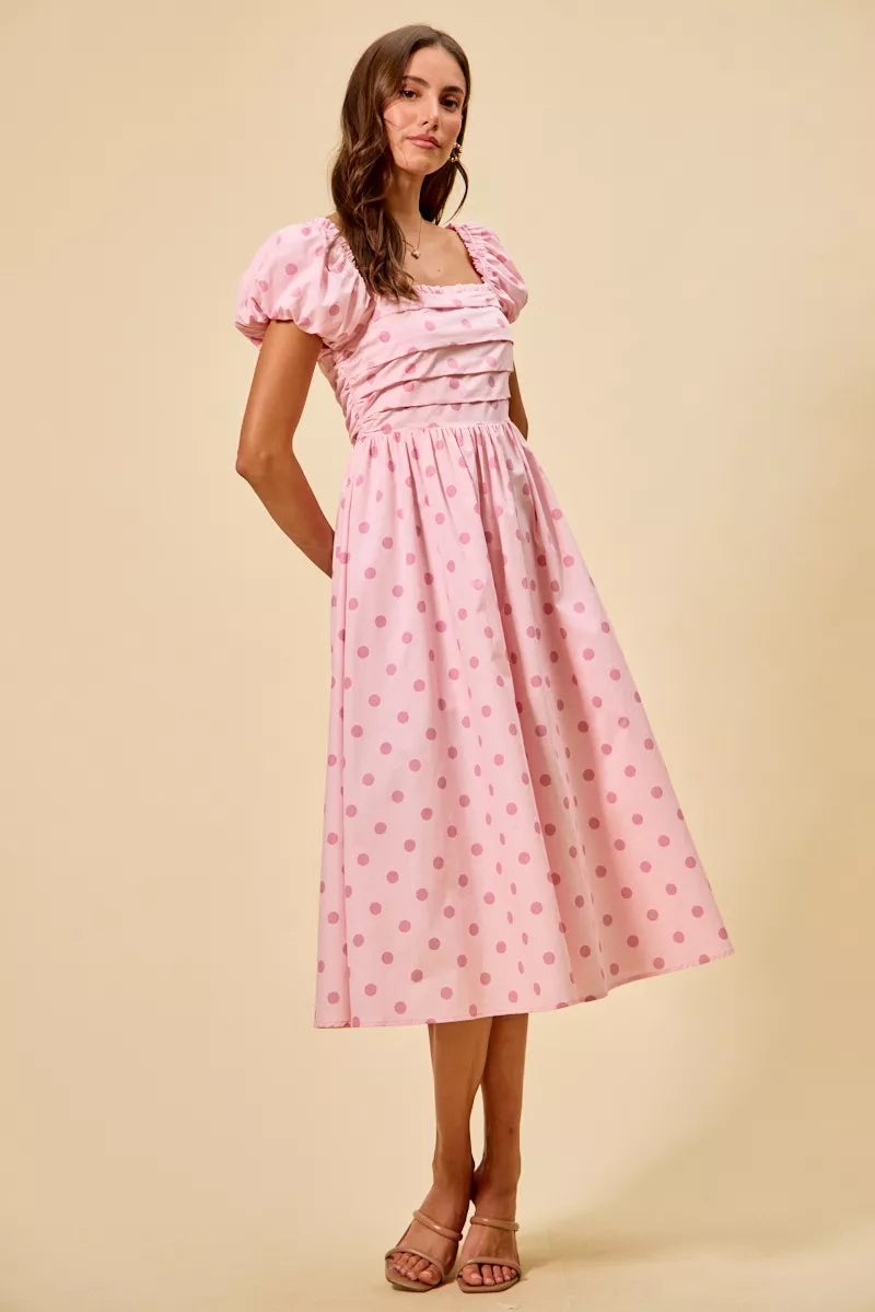 Front view of blush pink polka dot cotton midi dress featuring puff sleeves and pleated waist detailing | AVAH Collections

