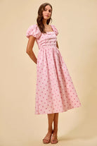 Front view of blush pink polka dot cotton midi dress featuring puff sleeves and pleated waist detailing | AVAH Collections
