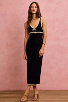 Front view of woman wearing a black cotton knit midi dress with contrast cream trim and tie front detail | AVAH Collections

