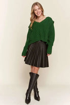 Full length view of Emerald Isle green cable knit sweater styled with a chocolate brown pleated mini skirt and tall boots.