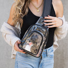 Woman wearing clear stadium-approved sling bag with adjustable black shoulder strap
