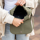 Person holding an open green bag with a blurred background