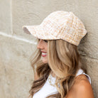 Woman wearing cream tweed baseball cap with subtle sequin detail
