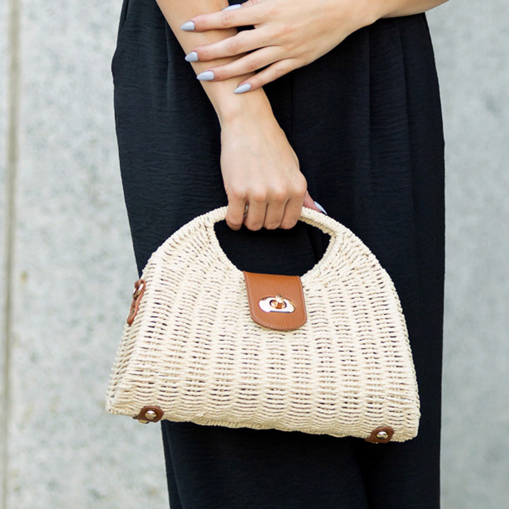 Straw crossbody bag with vegan leather and fixed top handle and removable crossbody strap complete with a fold over clasp and gold hardware, in straw front view