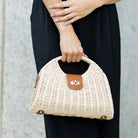 Straw crossbody bag with vegan leather and fixed top handle and removable crossbody strap complete with a fold over clasp and gold hardware, in straw front view