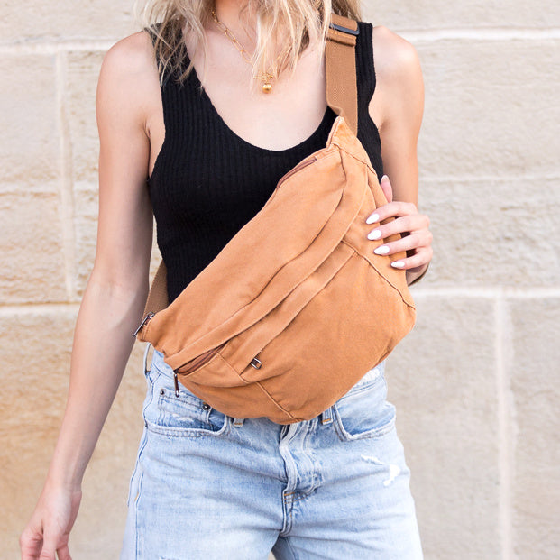 Person wearing a camel canvas oversized crossbody sling bag with a neutral background