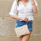 Model wearing cream woven straw crossbody with fringe flap detail, styled with a white blouse and denim shorts-AVAH
