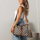 Woman wearing cognac and cream checkered hobo shoulder bag indoors.