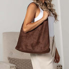 Side view of woman wearing slouchy mocha suede-look hobo bag.