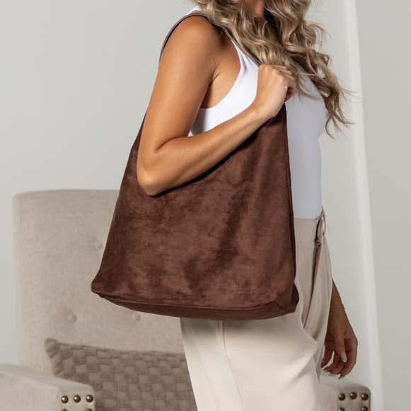 Side view of woman wearing slouchy mocha suede-look hobo bag.