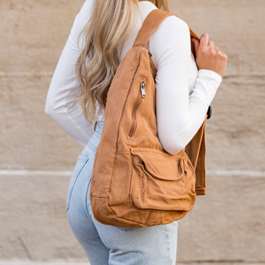 Person wearing a tan backpack against a neutral background