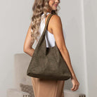 Woman wearing olive suede-look hobo bag indoors.