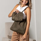 Olive suede-look hobo bag and matching pouch carried by a woman.