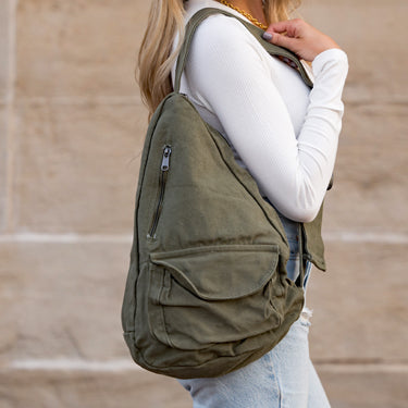 Person wearing a green backpack against a beige wall