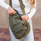 Person holding a green shoulder bag with a blurred background