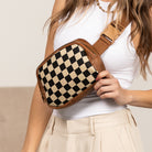 AVAH-Woman holding a brown vegan leather checkered fanny pack with brown canvas straps on a white background