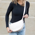 Person holding a bone shoulder bag against a neutral background