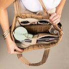 Person holding a Mocha travel tote open with a laptop and other items inside on a neutral background