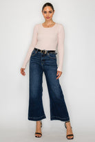Model wearing dark wash wide leg jeans with long sleeve knit top