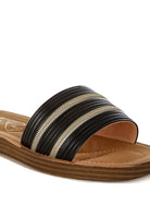 Close-up of black sandals with zipper-inspired trim and ribbed detailing.