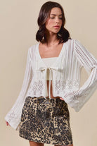 Woman wearing off white pointelle knit tie front cardigan with leopard print skirt
