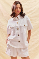 Woman wearing a white denim matching set with button front shirt and shorts

