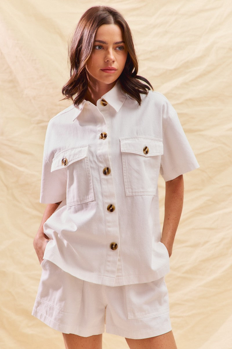 Woman wearing a white denim matching set with button front shirt and shorts
