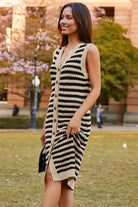 Side view of tan and black striped sweater dress highlighting ribbed texture and knee-length cut.
