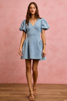 light wash denim mini dress with puff sleeves, V neckline, and fit and flare silhouette front view.
