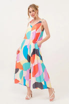 Model wearing a colorful abstract print wide leg jumpsuit with adjustable tie straps and flowy silhouette | AVAH Collections
