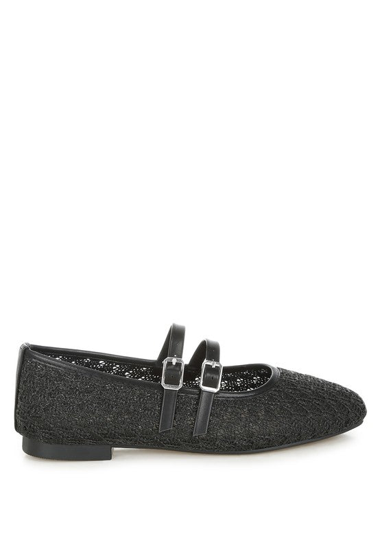 Black woven raffia ballet flats with faux leather straps and double buckle accents, side profile.