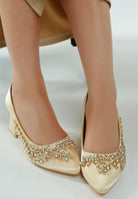 Close-up of beige satin pointed-toe heel with crystal detailing
