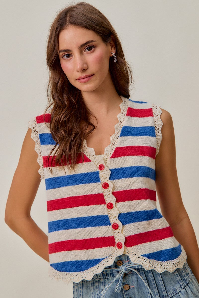 Woman wearing a red, ivory, and blue striped knit vest with scalloped trim and red buttons

