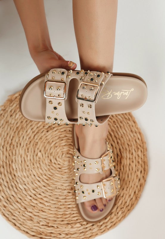  Beige studded slide sandal with soft insole shown in hand, buckle and sole details visible