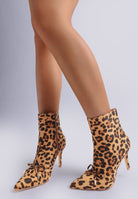 Leopard print ankle boots worn by a person on a light gray background