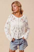 Woman wearing ivory crochet knit cardigan with button front and denim shorts front view

