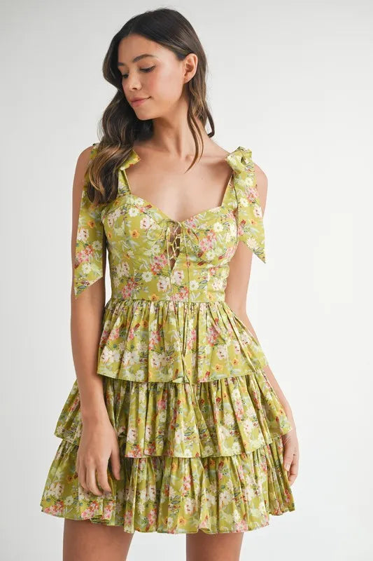 Lime floral tiered mini dress with ruffle skirt and adjustable bow shoulder straps angled front view
