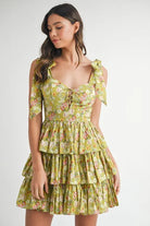 Lime floral tiered mini dress with ruffle skirt and adjustable bow shoulder straps angled front view
